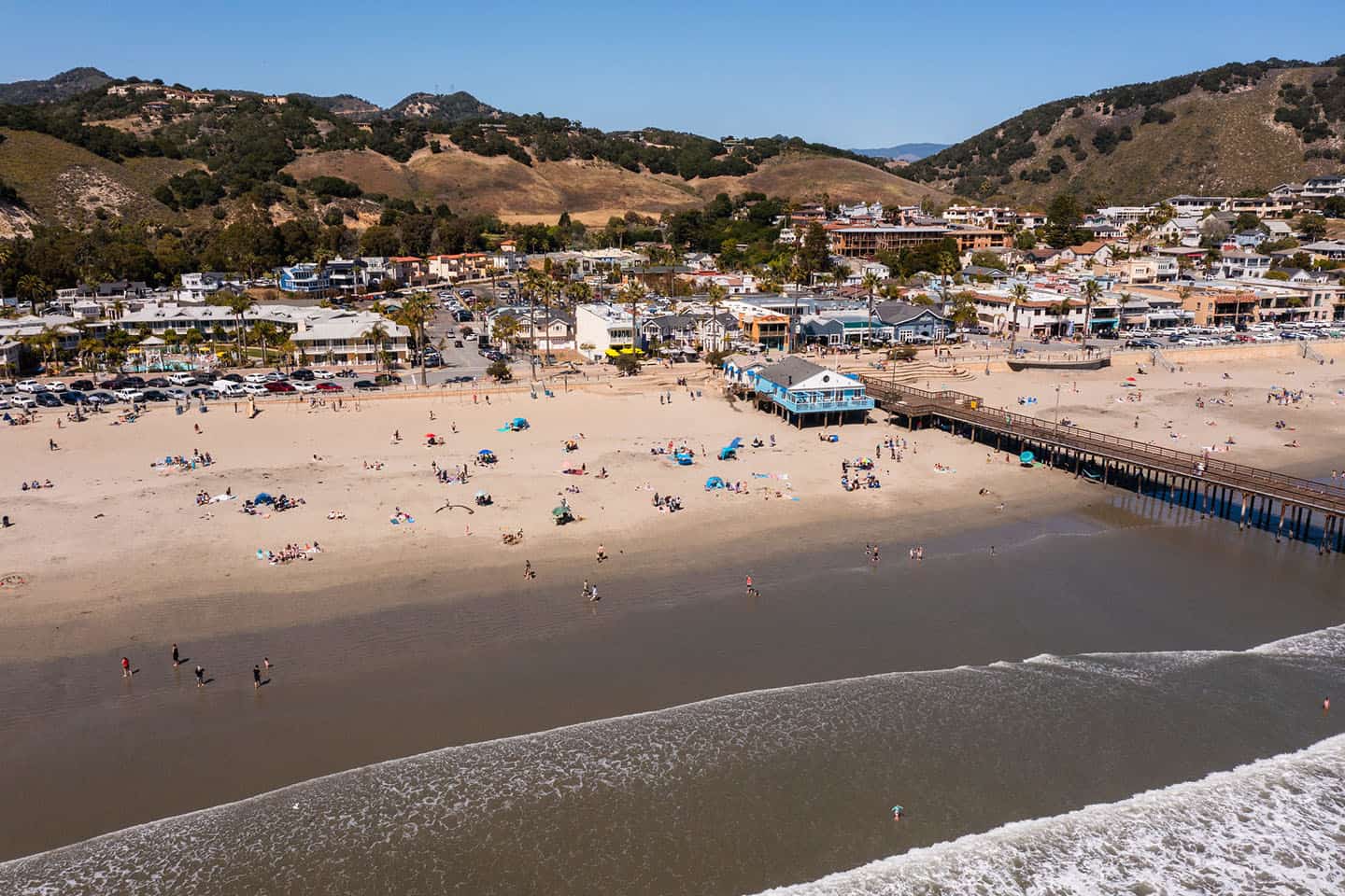 Aerial view of a beach with a pier and buildings in the background.